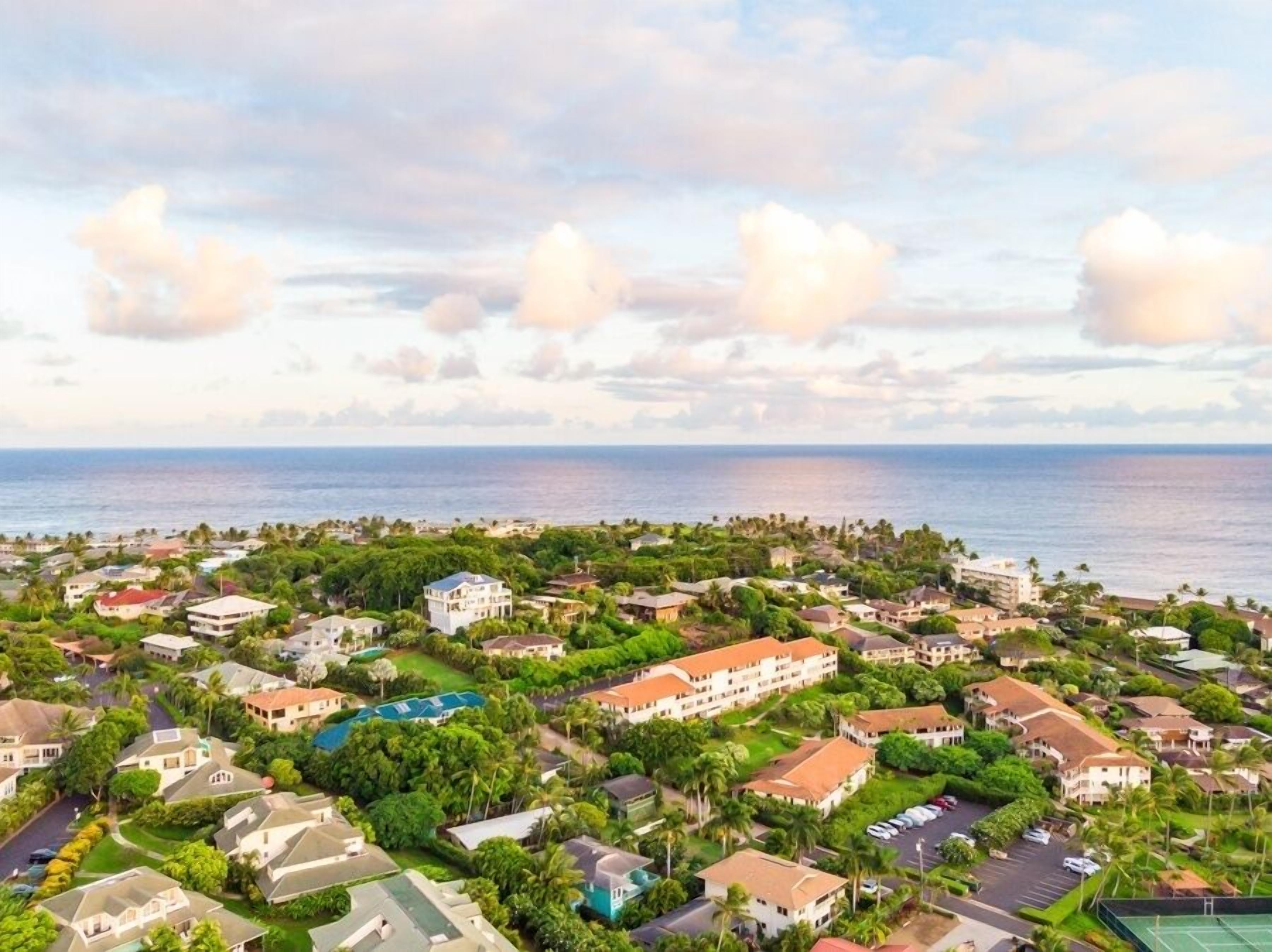 Un quartier résidentiel en bord de mer, avec des maisons, un grand bâtiment doté d’un toit rouge et une vue sur l’océan.