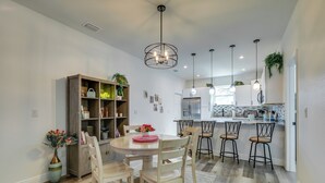 Una cocina moderna con una isla central, taburetes de bar e iluminación colgante.