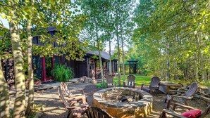 A patio area with Adirondack chairs, a stone fire pit, and a wooden deck. - Stunning Truckee Home w/ Private Patio & Gas Grill (Truckee)