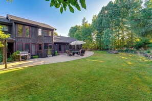 A two-story house with a patio area featuring outdoor furniture and a grill.