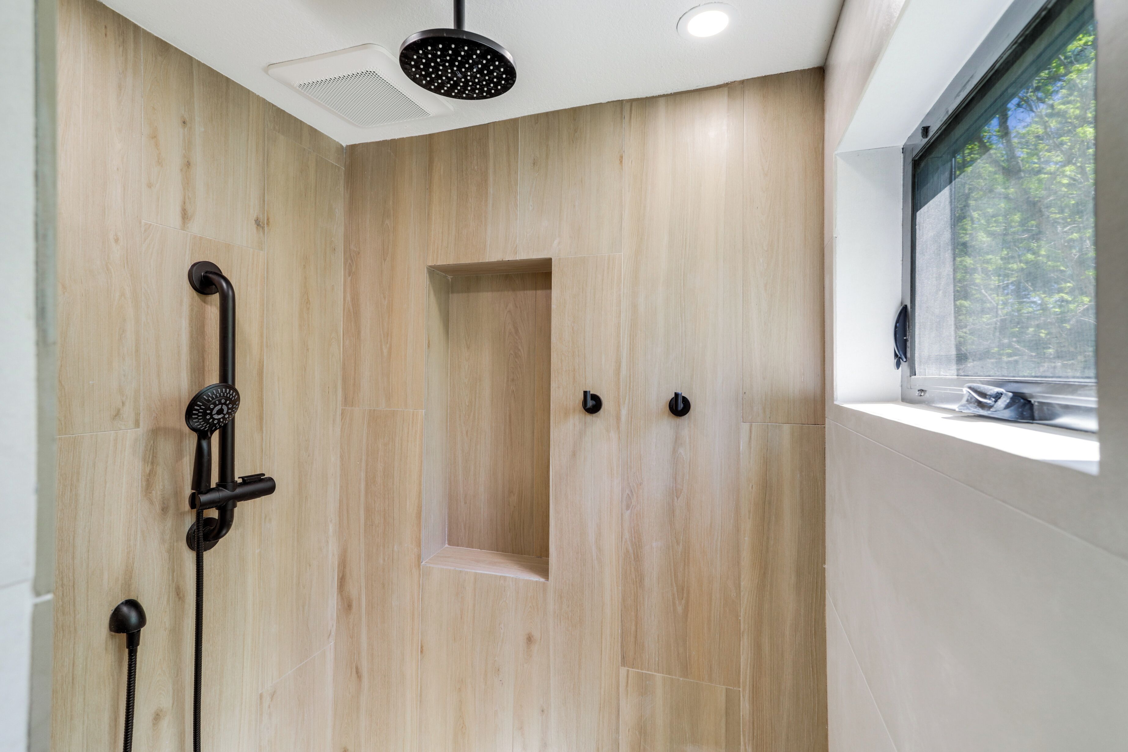 A modern shower with a rain showerhead, a handheld showerhead, and a handheld massager.