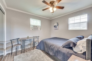 A bedroom with a bed, a desk, a chair, and a ceiling fan.
