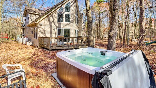 A wooden cabin with a hot tub in a wooded area. - Serene Poconos Cabin w/ Hot Tub & Beach Access! (Albrightsville)