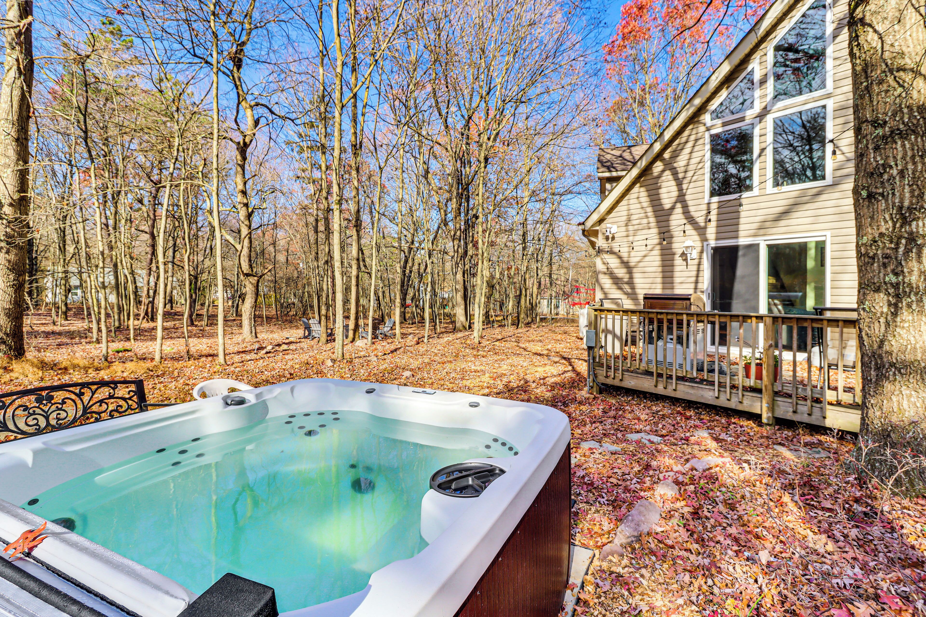 Een hottub in een beboste achtertuin, met een huis op de achtergrond.