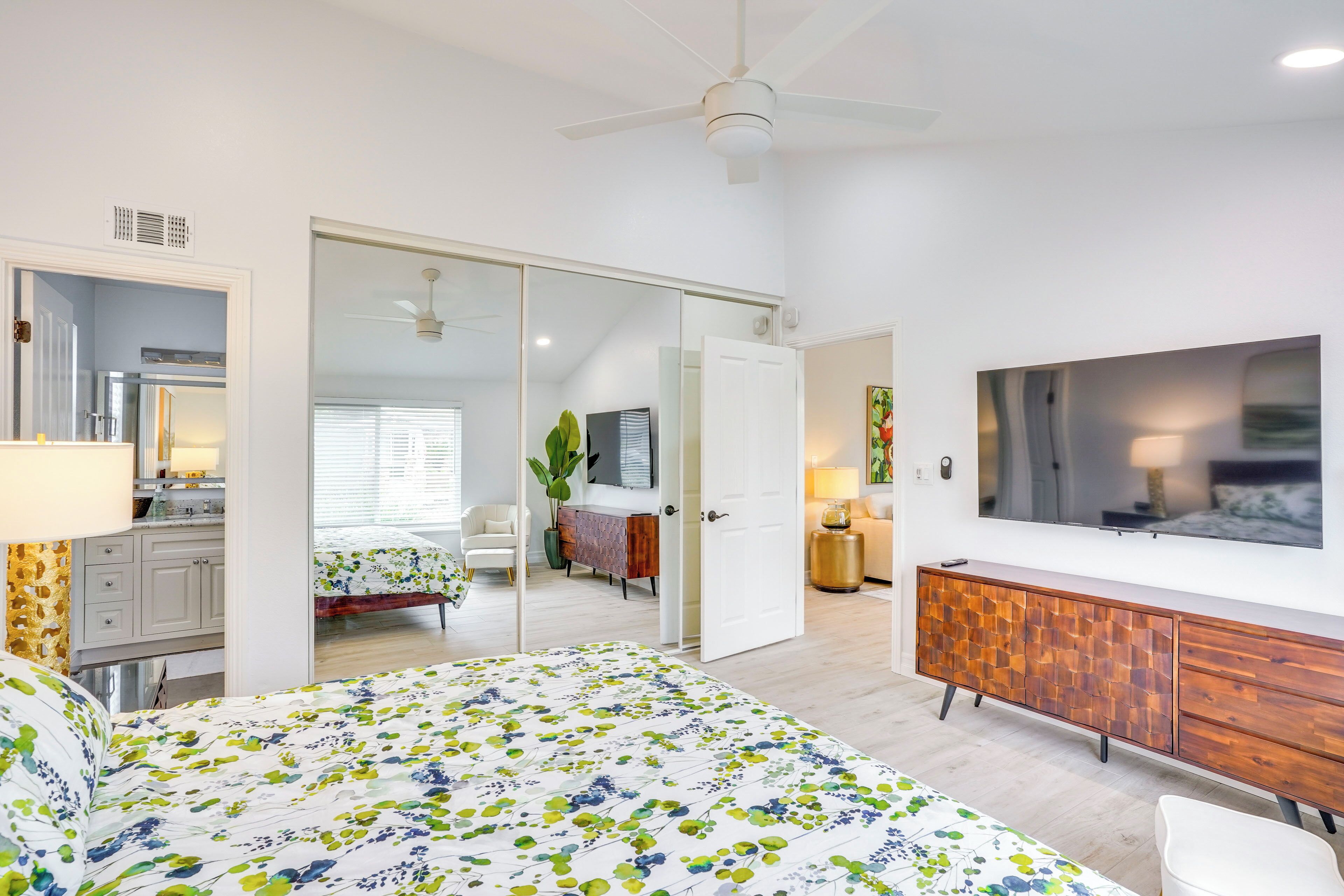 A modern bedroom with a bed, a TV, a wardrobe, and a sliding door leading to another room.