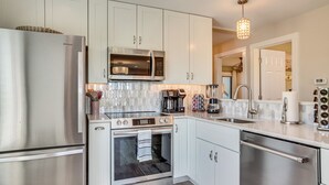 A modern kitchen with stainless steel appliances, white cabinetry, and a built-in oven.