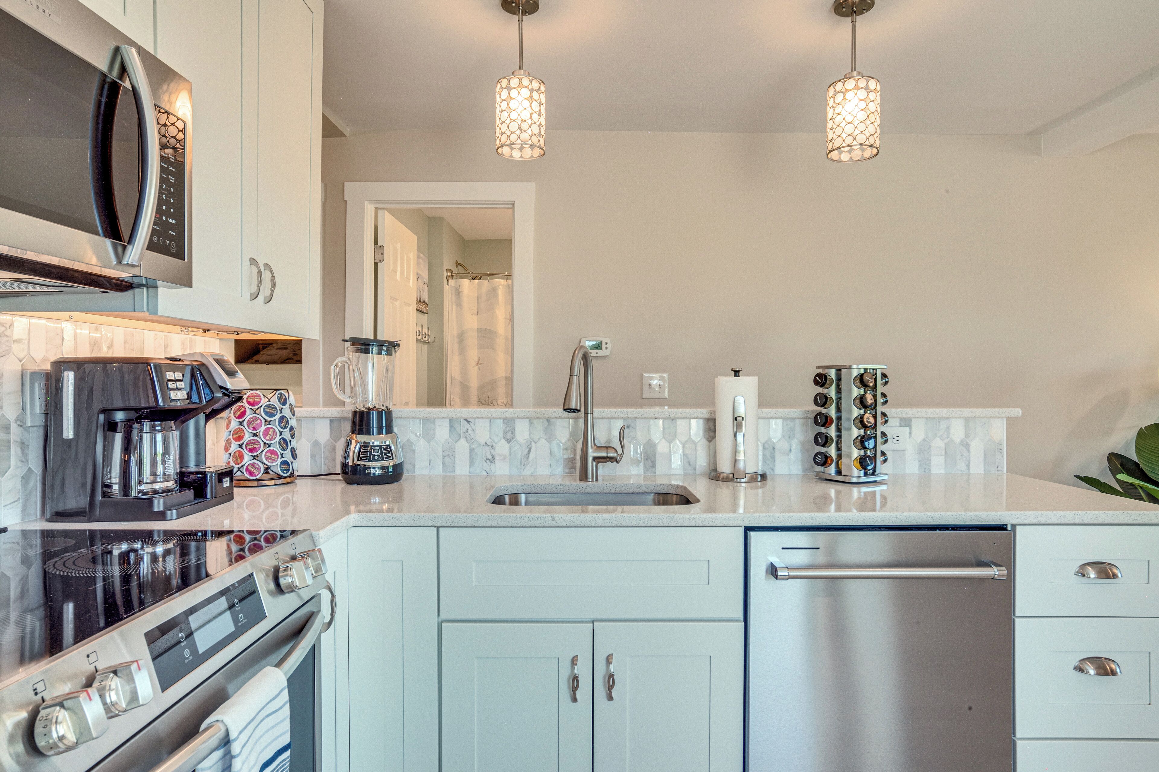 A modern kitchen with stainless steel appliances, a white countertop, and pendant lighting.