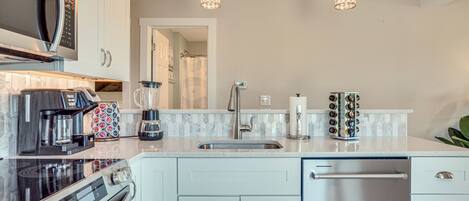 A modern kitchen with stainless steel appliances, a white countertop, and pendant lighting.