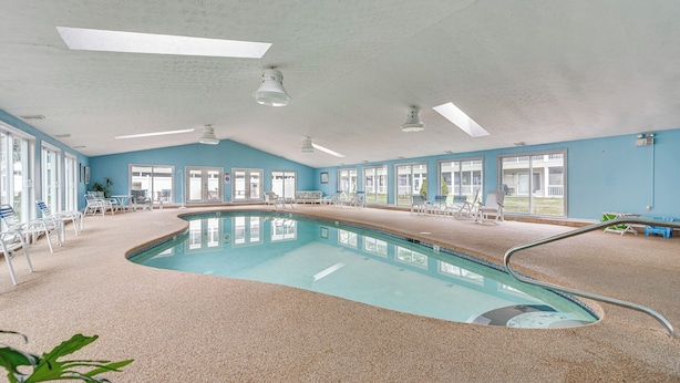A large indoor swimming pool with clear blue walls, multiple windows, and ceiling fans. - Livin Wells' Retreat, 2 Mi to Drakes Island Beach (Wells)