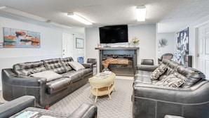 A living room with two leather sofas, a flat-screen TV, a fireplace, and artwork on the walls. - Livin Wells' Retreat, 2 Mi to Drakes Island Beach (Wells)