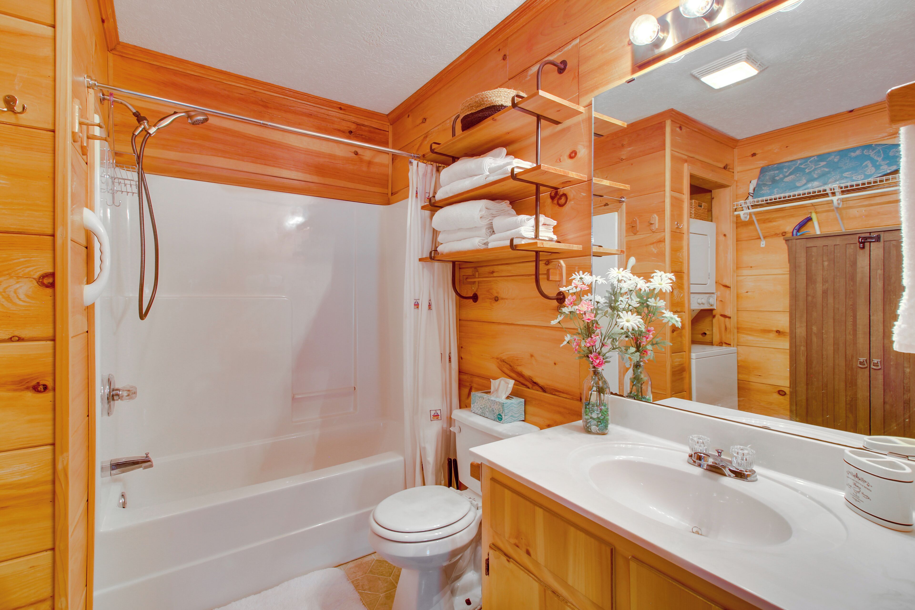 Ein Badezimmer einer Holzhütte mit Badewanne, Toilette und Waschtisch mit Spiegel.