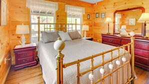 A wooden cabin bedroom with a bed, nightstands, and a dresser. - Cozy Cabin w/ Grill & Fire Pit By Dale Hollow Lake (Byrdstown)