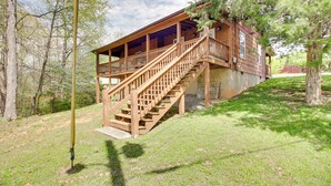 A wooden cabin with a covered porch and a staircase leading to the main floor. - Cozy Cabin w/ Grill & Fire Pit By Dale Hollow Lake (Byrdstown)