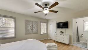 A bedroom with a bed, a ceiling fan, a TV, a dresser, and a bathroom visible through an open door. - Inviting Columbus Home w/ Deck: 7 Mi to Downtown! (Columbus)