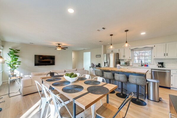 A modern kitchen with a dining area, white cabinetry, and a large island.