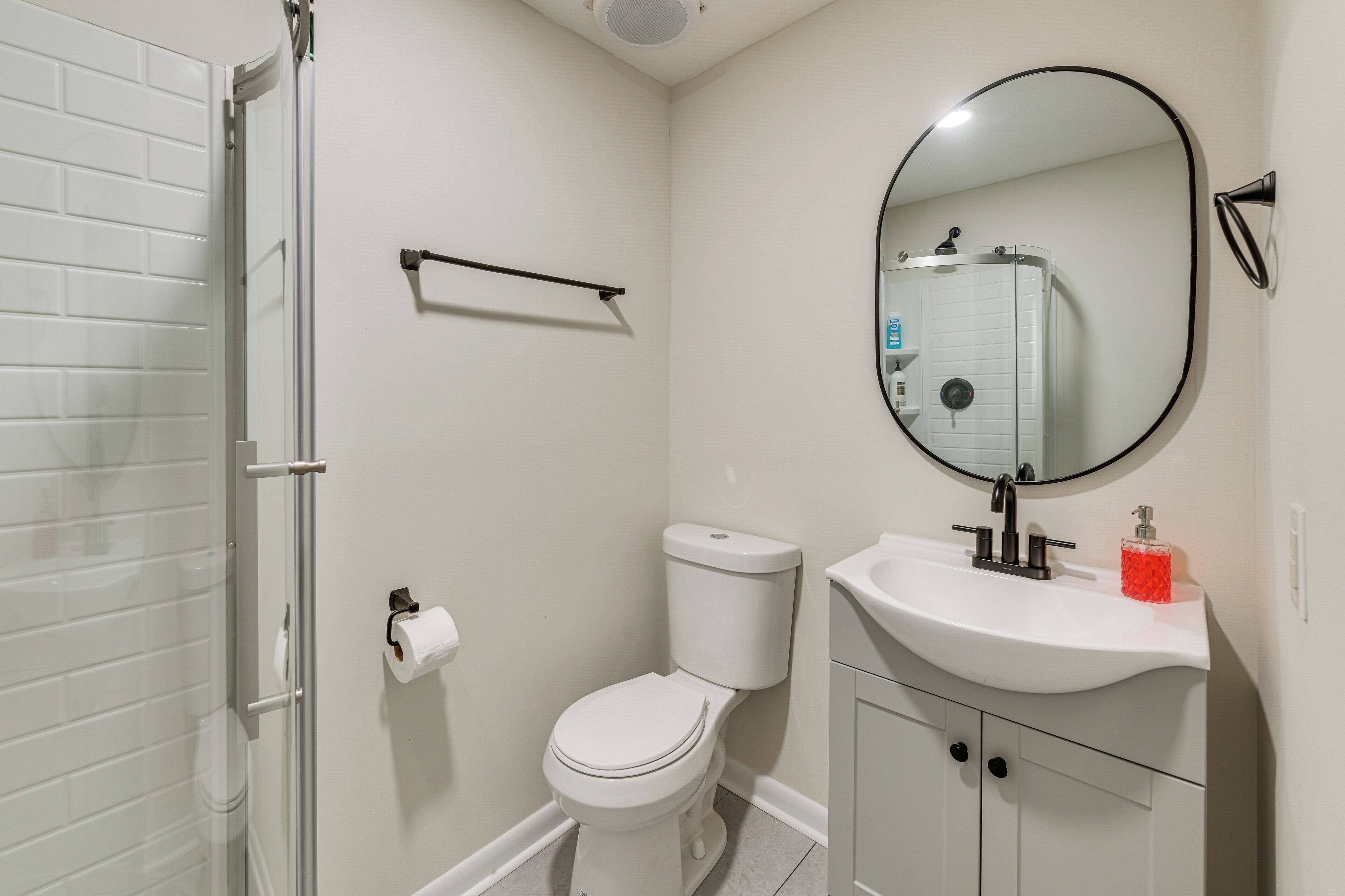 A bathroom with a toilet, sink, mirror, and shower.