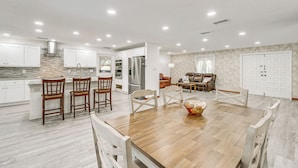 Una cocina amplia con armarios blancos, una mesa de comedor de madera y un horno empotrado.