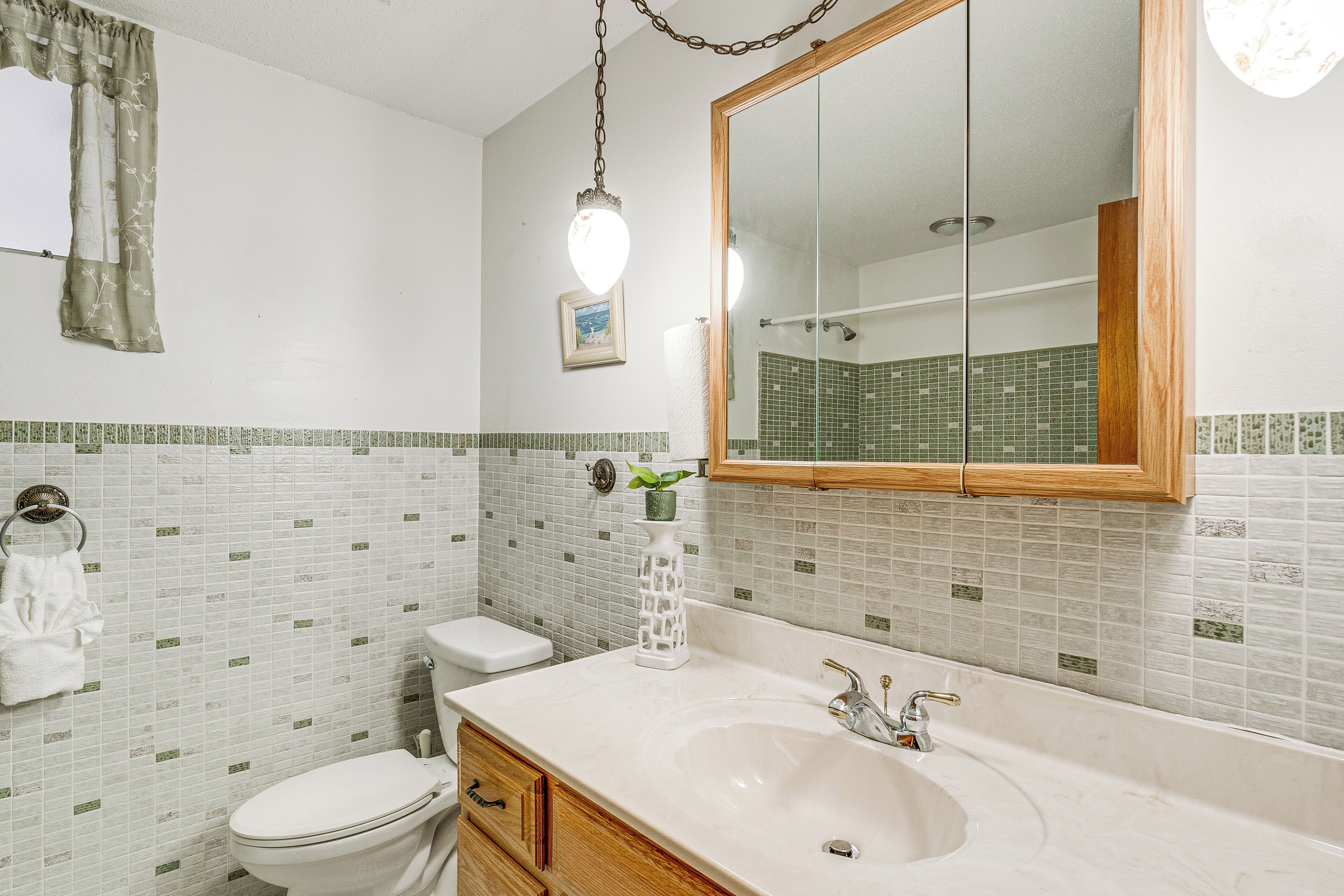 A bathroom with a white sink, wooden vanity, and a large mirror.