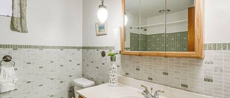 A bathroom with a white sink, wooden vanity, and a large mirror.
