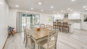 Una cocina amplia con armarios blancos, una mesa de comedor de madera y una isla grande con taburetes de bar.