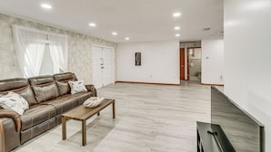 Amplia sala de estar con un sofá de cuero marrón, una mesa de centro de madera y un televisor de pantalla plana.