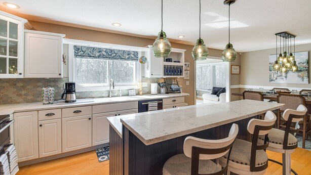A modern kitchen with white cabinets, a marble island, and pendant lighting. - Rock Island Home w/ Private Yard & Fire Pit Table! (Rock Island)