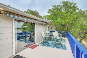 A covered outdoor patio with a table and chairs, a blue railing, and a view of trees. - Waterfront Lake Buchanan Cottage w/ Kayaks! (Burnet)
