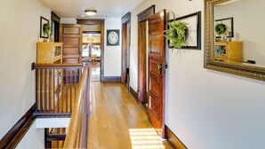 A wooden staircase with a railing, a wall clock, and a mirror with a decorative frame. - Charming Winterset Vacation Rental w/ Yard & Patio (Winterset)