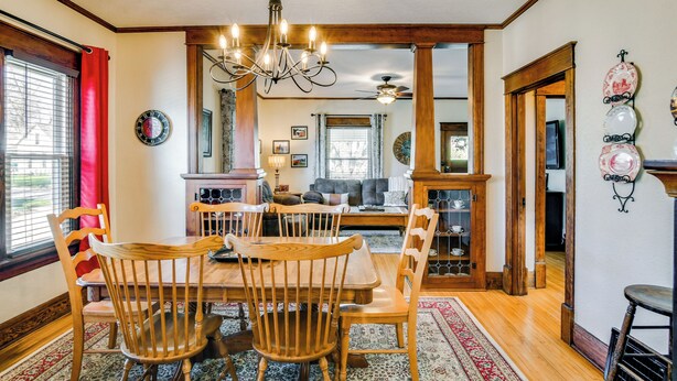 A dining area with a wooden table and chairs, a chandelier, and a view into the living room. - Charming Winterset Vacation Rental w/ Yard & Patio (Winterset)