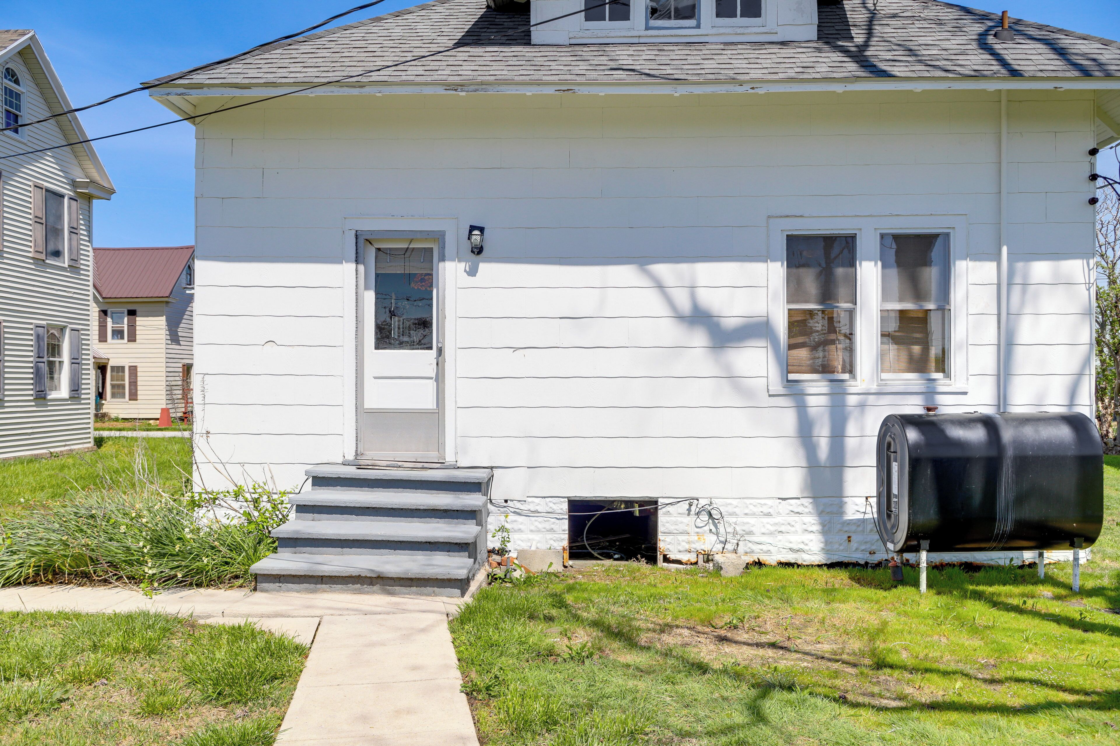 A white house with a front door, a small porch, and a mailbox.