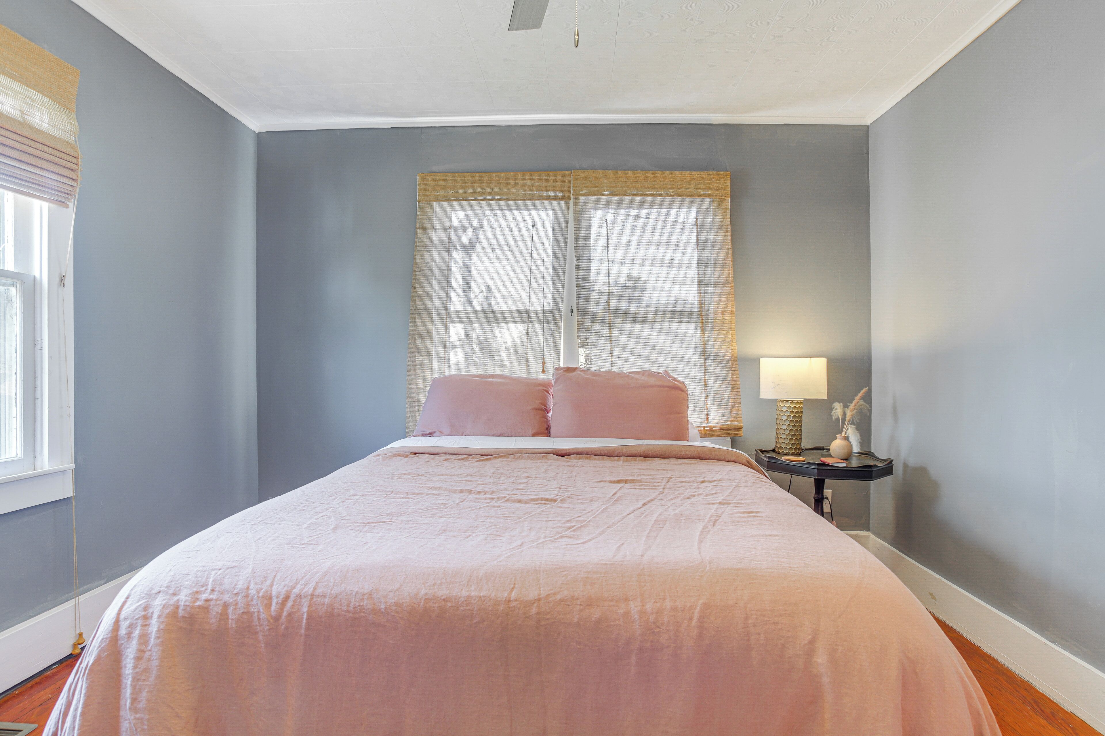 Une chambre à coucher avec un grand lit, une table de chevet avec une lampe et une fenêtre avec des stores.