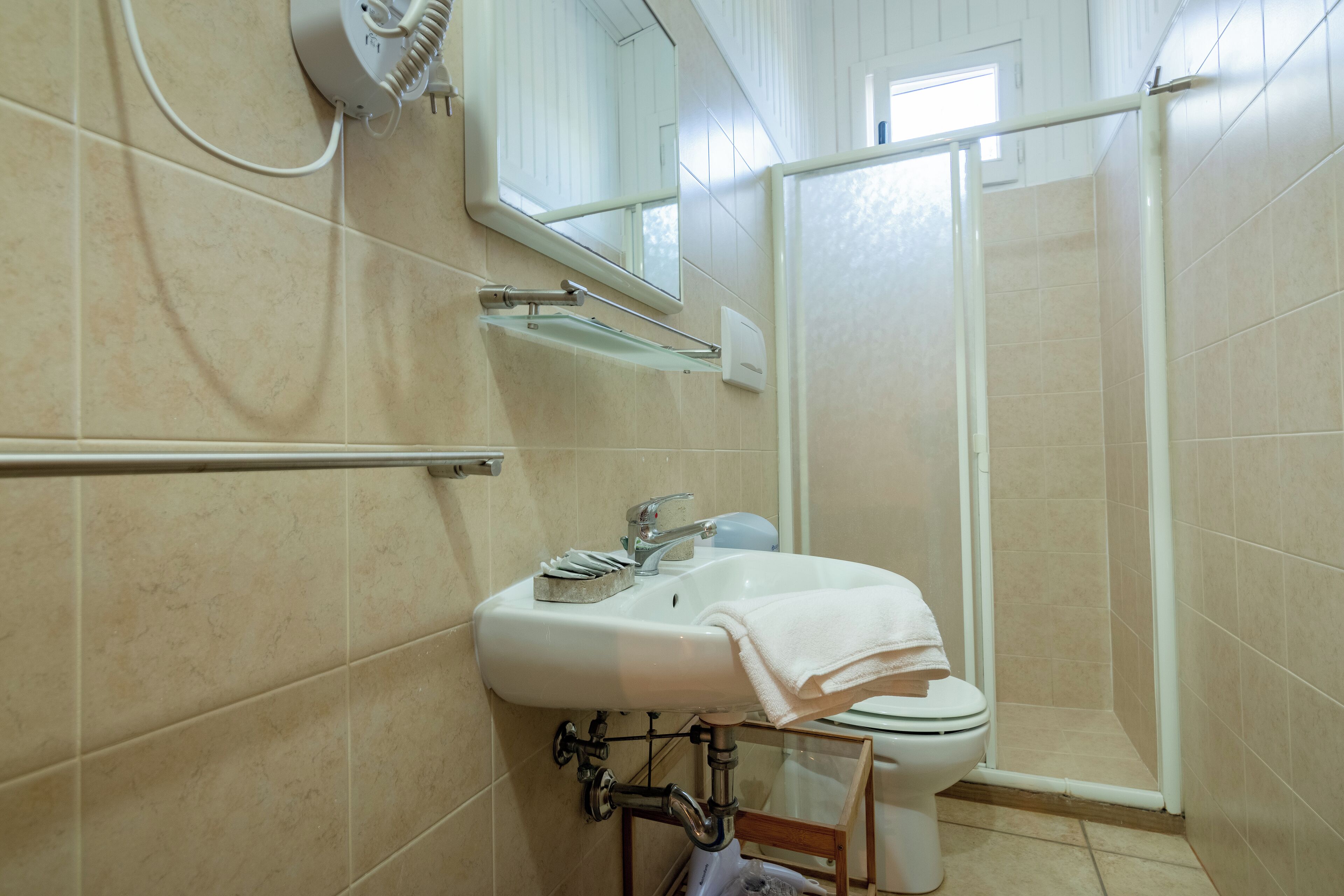 A bathroom with a white sink, mirror, and shower enclosure.