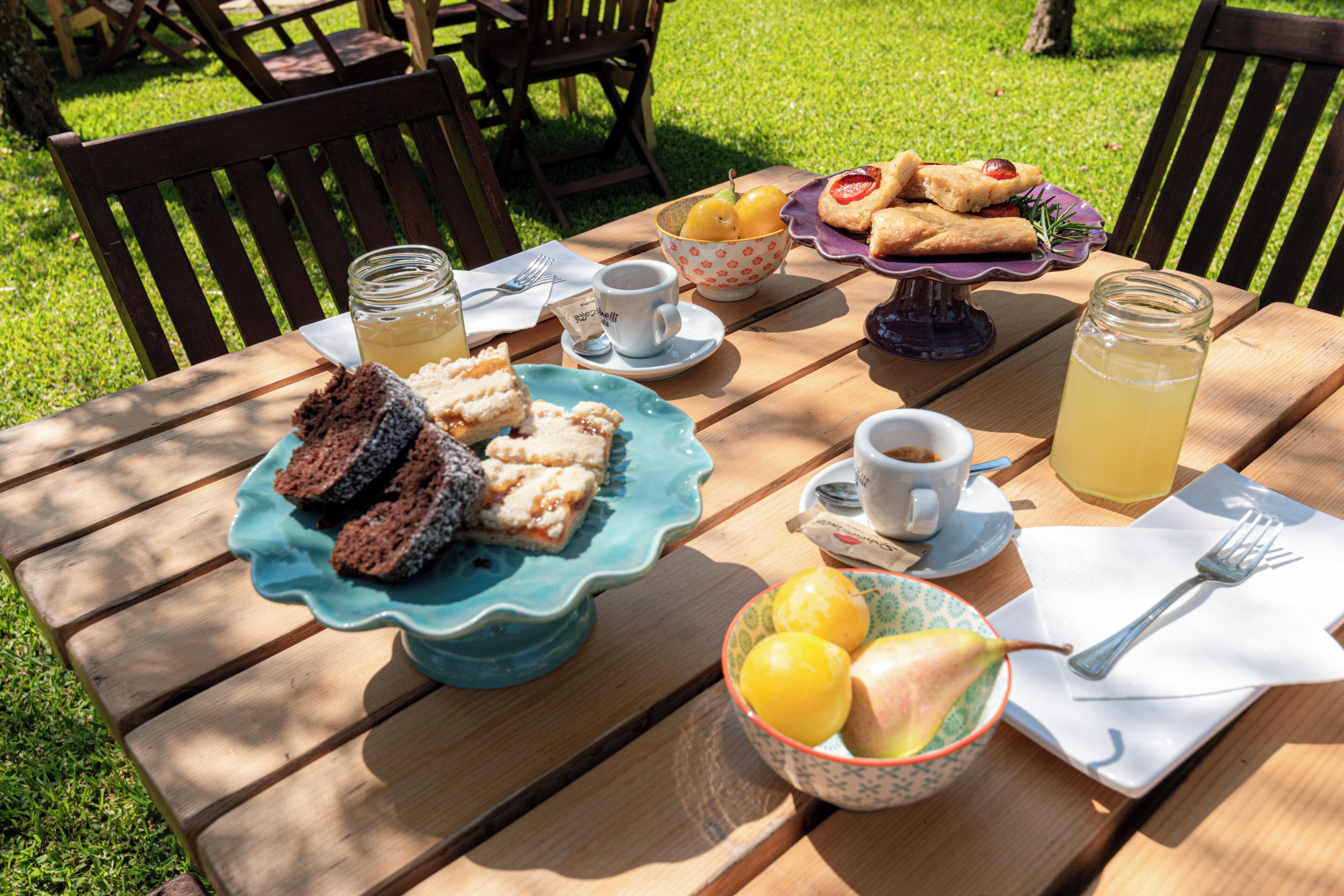 Une table en bois sur laquelle sont disposés divers aliments, notamment des sandwichs, des pâtisseries et un saladier de fruits.