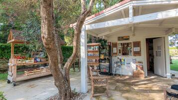 Un marché de plein air à l’ambiance rustique, avec des étals en bois, un espace pour s’asseoir et une structure couverte portant une enseigne.