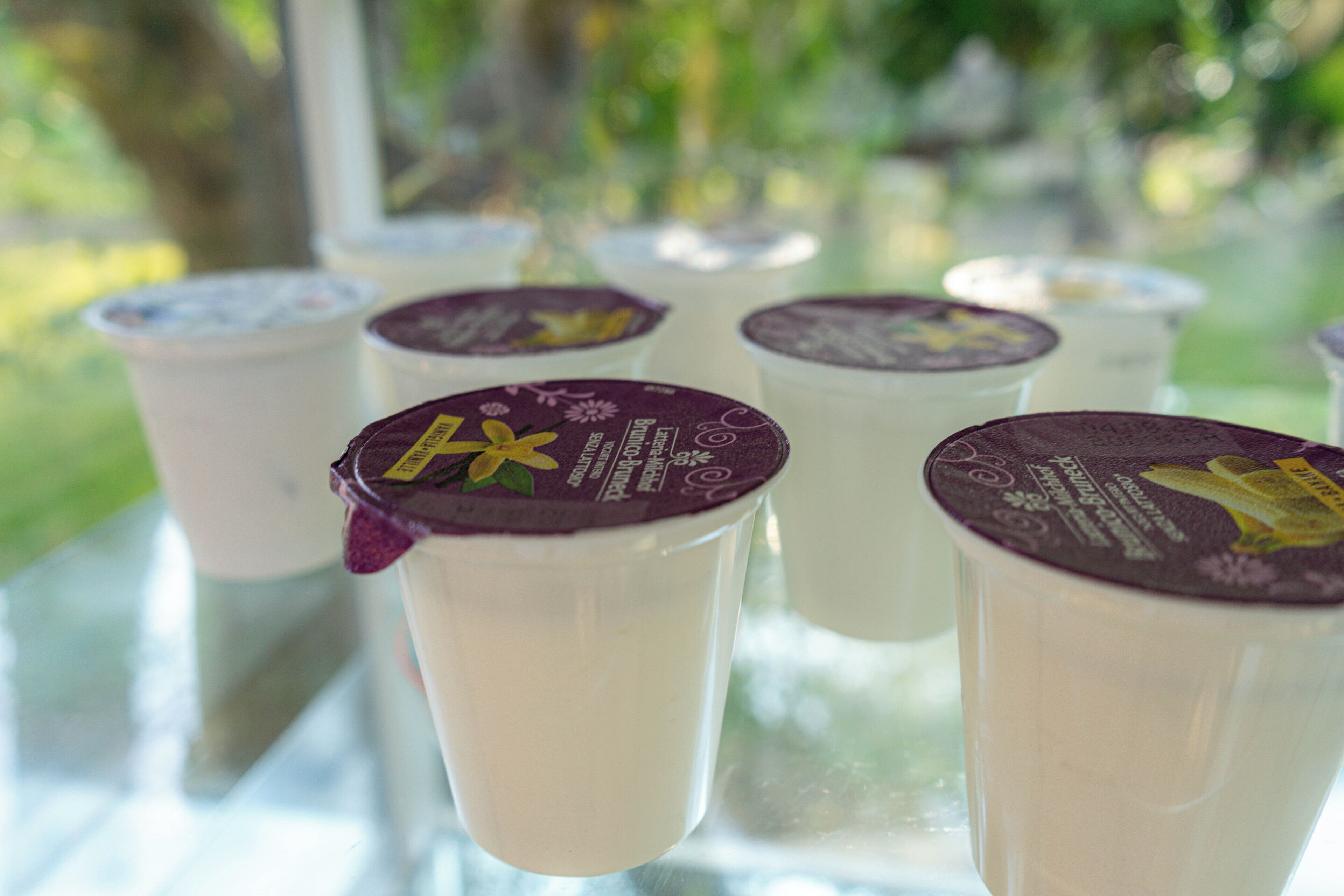 A row of yogurt cups with purple lids on a table.