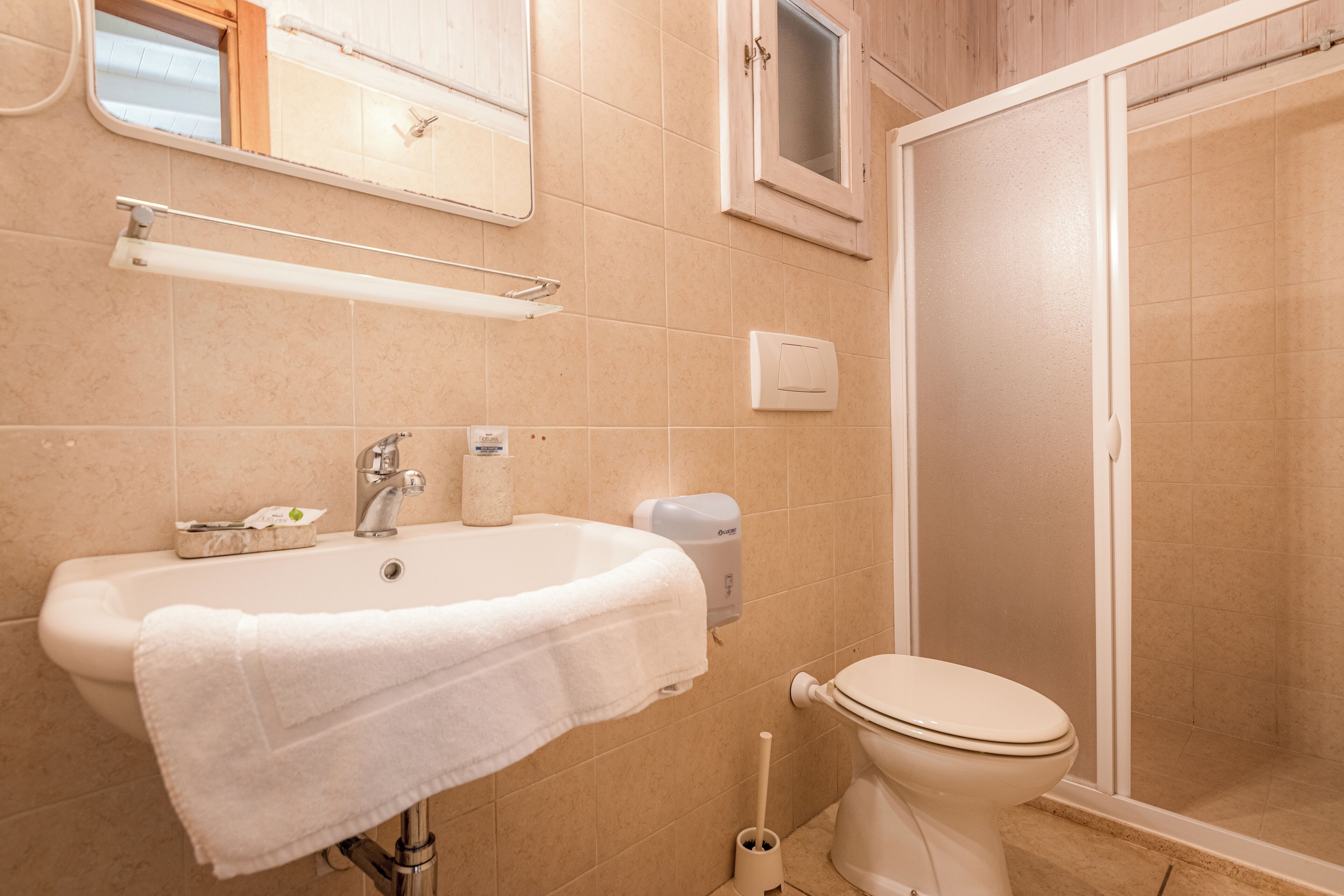 A bathroom with a sink, mirror, toilet, and shower.