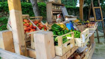 Een houten kist met een presentatie van vers fruit en groenten, waaronder tomaten, paprika's en uien.