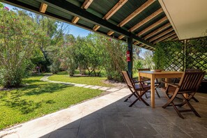 An outdoor patio with a wooden table and chairs, surrounded by a garden with a stone pathway. - BIO AGRITURISMO SALOS (Otranto)