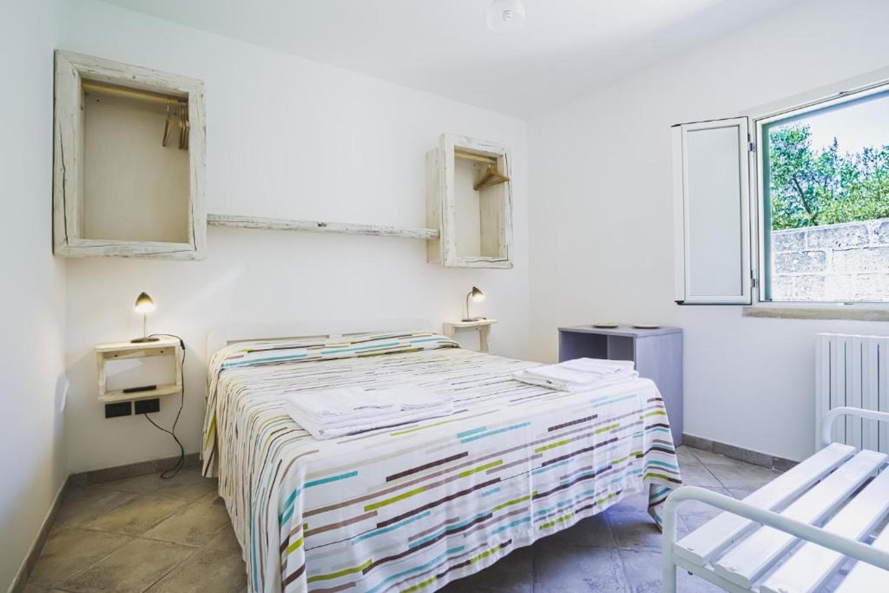 Een slaapkamer met een bed, nachtkastjes, een raam en een radiator.