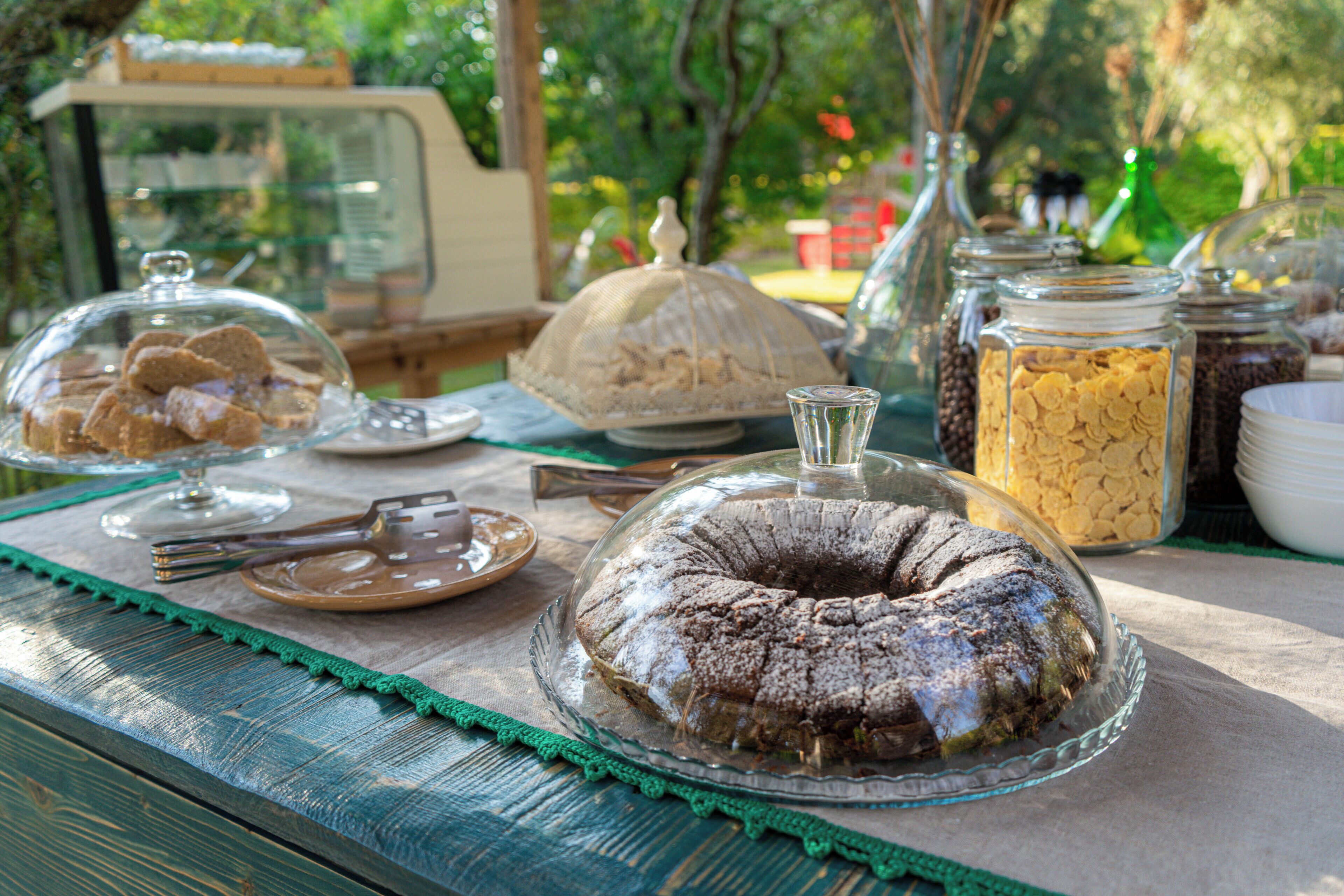 A table with a cake, a glass bowl, and jars of food.