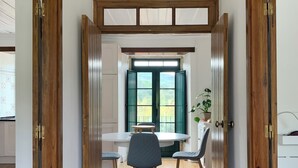 Ein Flur mit Holztüren, ein Essbereich mit Tisch und Stühlen sowie ein Fenster mit grünen Fensterläden.