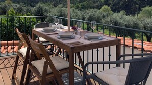 Eine Holzterrasse mit Esstisch, Sonnenschirm und Stühlen.