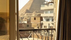 A room with a view of a pyramid and buildings. - Jimmy Pyramids Hotel  (Giza)
