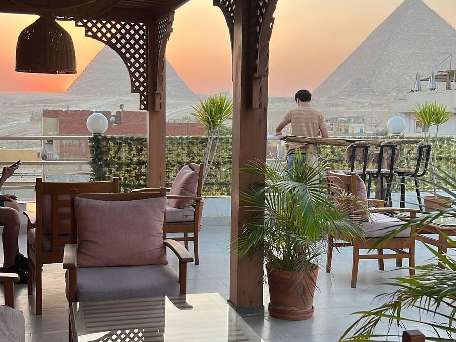 An outdoor seating area with tables and chairs, overlooking a mountainous landscape.