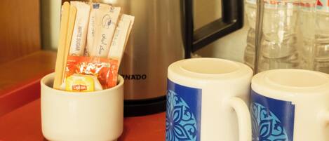 A tray with a coffee pot, two mugs with blue patterns, and packets of sugar and Lipton tea.