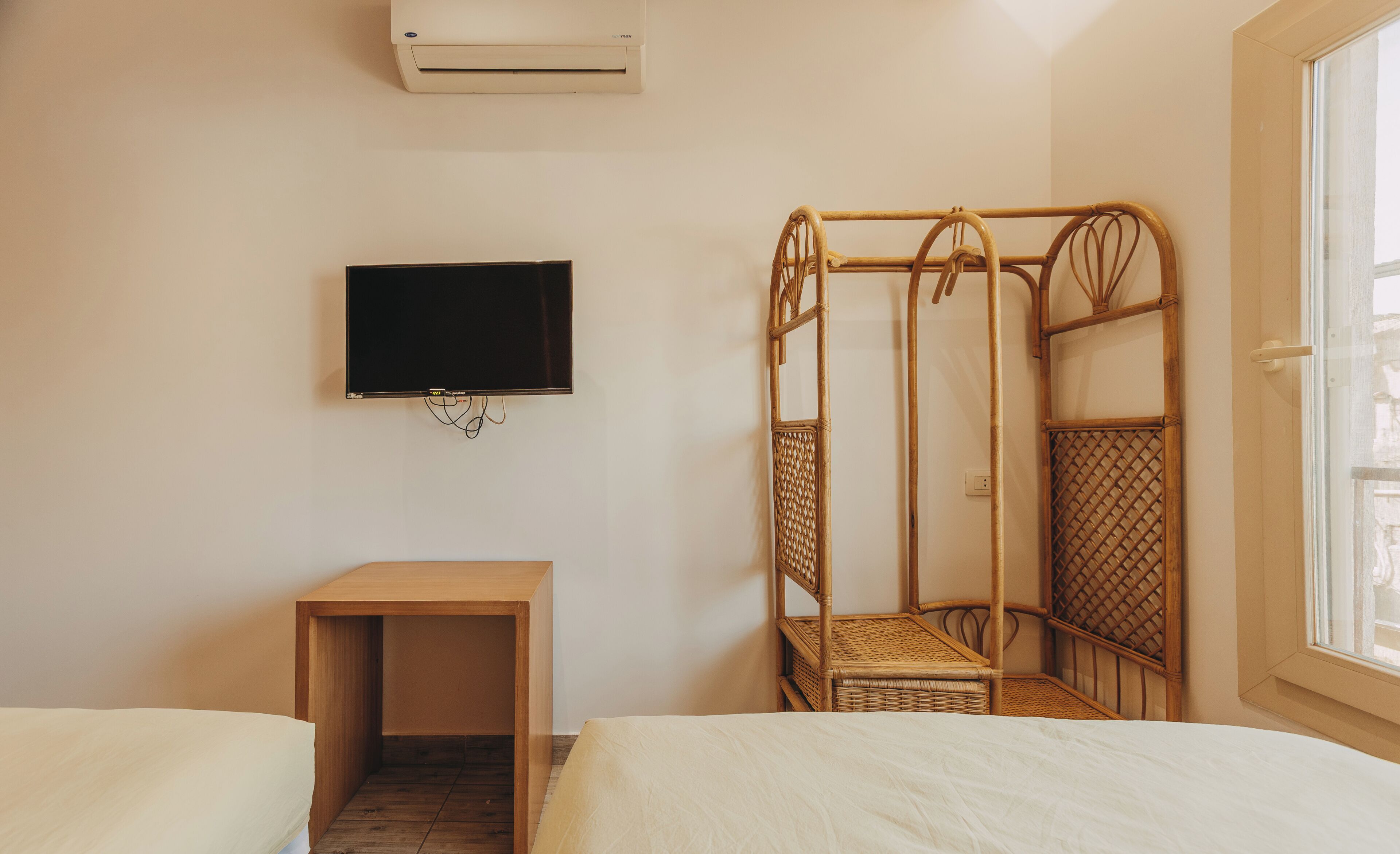A room with a bed, a small table, a TV, and a window.