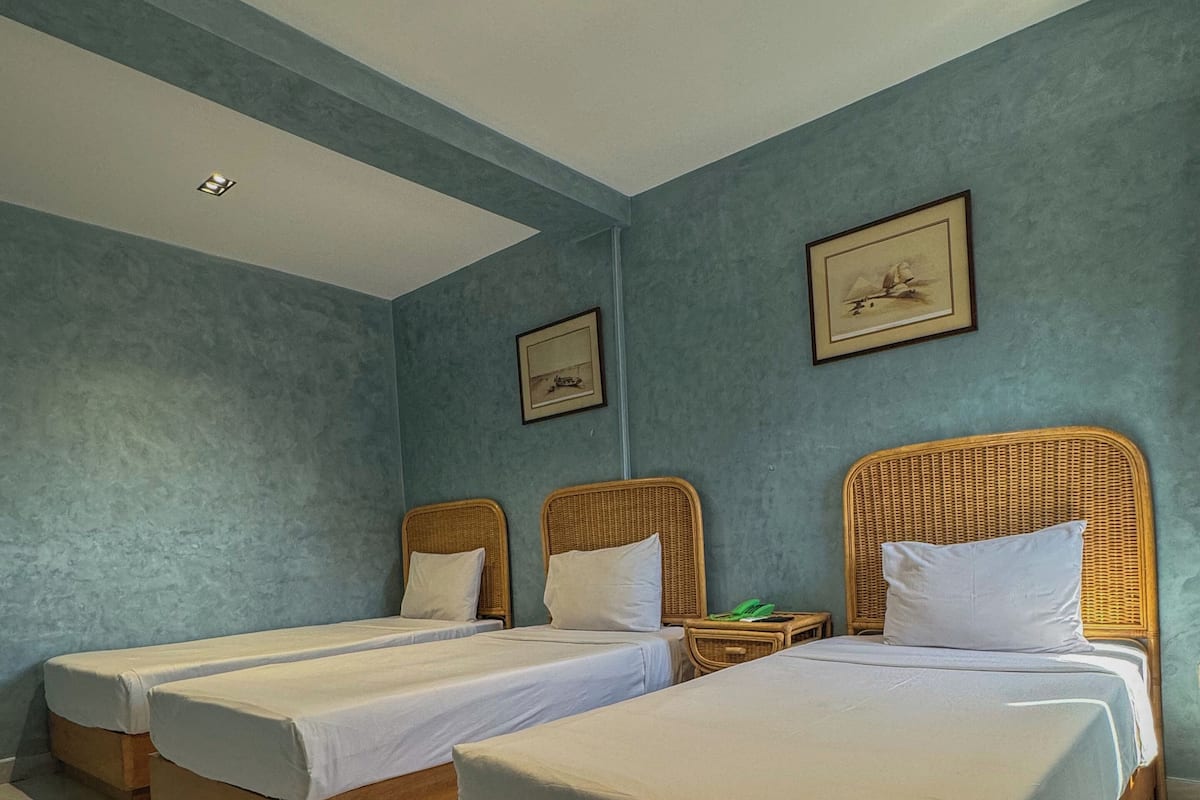 A hotel room with two single beds, a wooden headboard, a nightstand, and a framed picture on the wall.