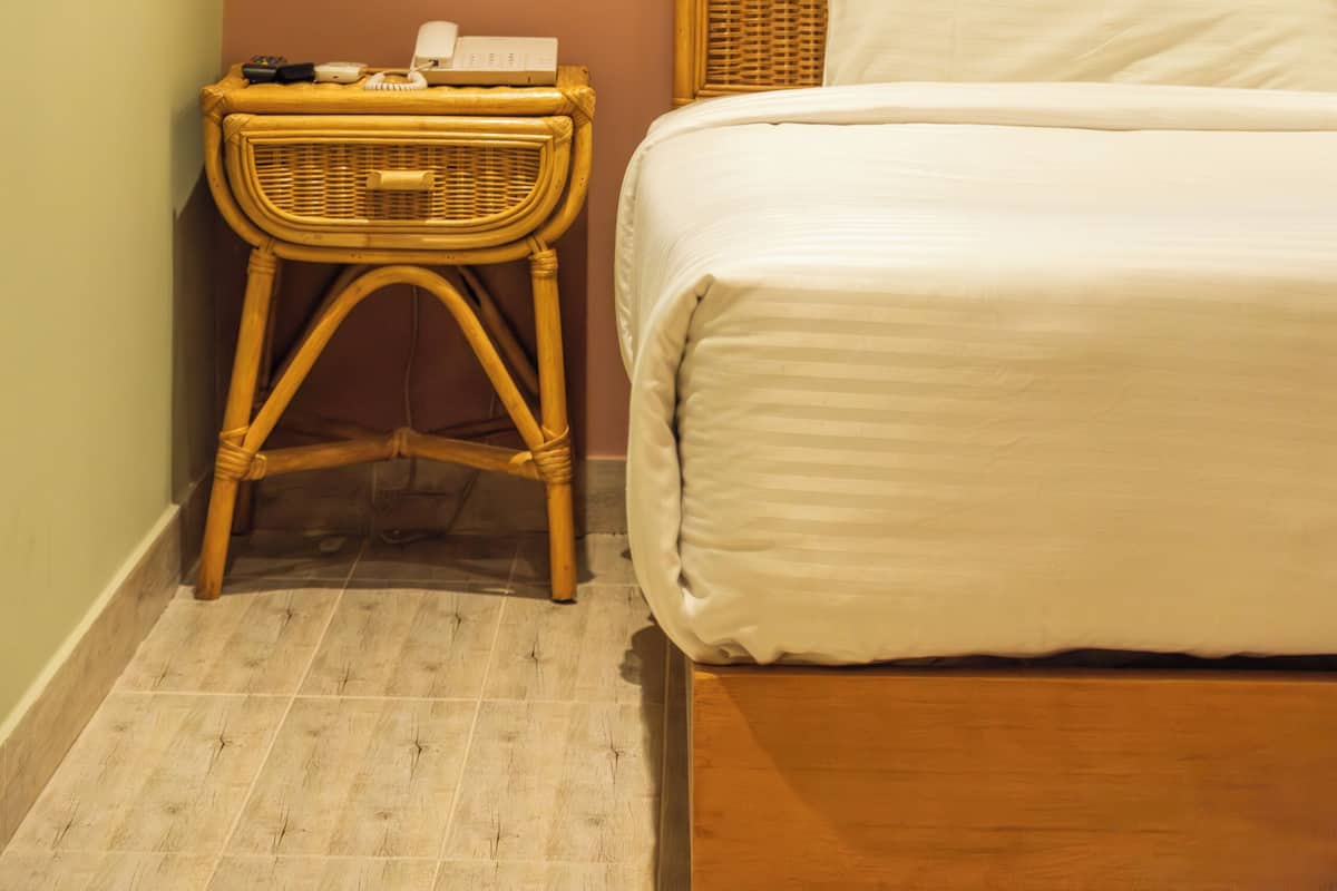 A bedroom with a wooden headboard, a white mattress, and a wicker nightstand with toiletries.