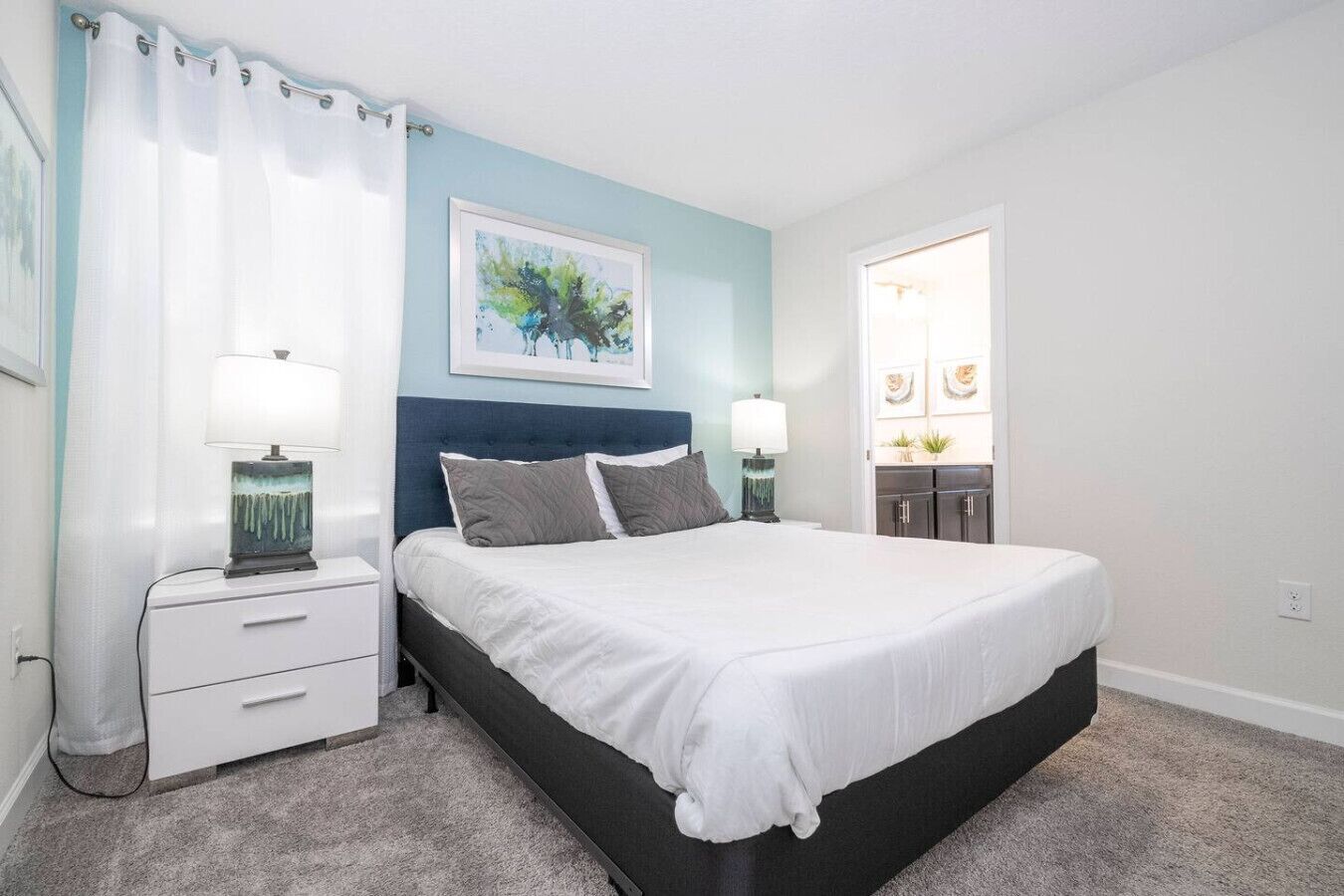 Une chambre à coucher comprenant un lit, des tables de chevet, une tête de lit, un tableau et une armoire.