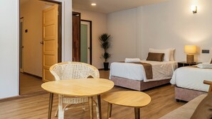 A hotel room with two beds, a small table, a chair, and a potted plant. - Mulyo Hotel (Port Dickson)